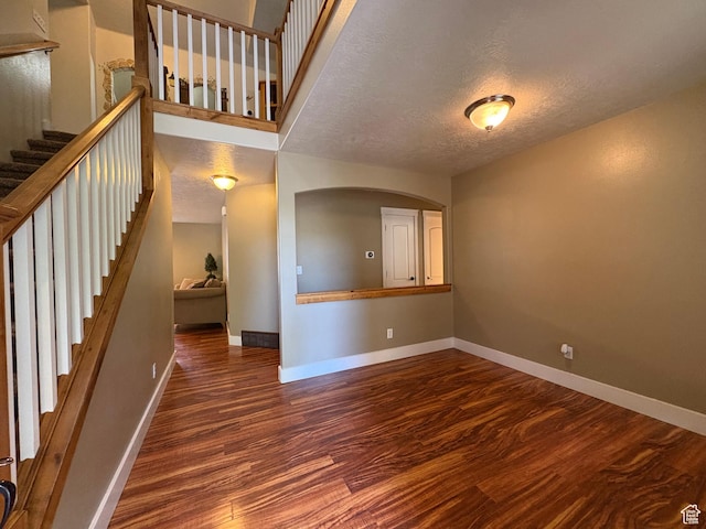 332 W Hillside S, Saratoga Springs, UT 84045 - unfurnished living room with wood finished floors, a textured ceiling, stairs, and arched walkways