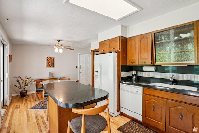4199 S Monarch Way, Salt Lake City, UT 84124 - kitchen featuring white appliances, dark countertops, brown cabinets, a breakfast bar, and light wood-style floors