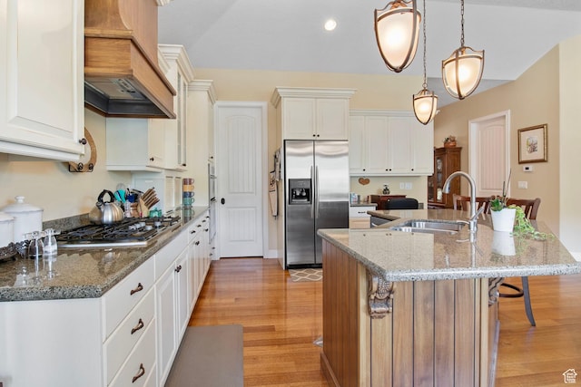 14599 S Chaumont Ct, Draper, UT 84020 - kitchen with appliances with stainless steel finishes, custom exhaust hood, a center island with sink, light wood finished floors, and a kitchen breakfast bar