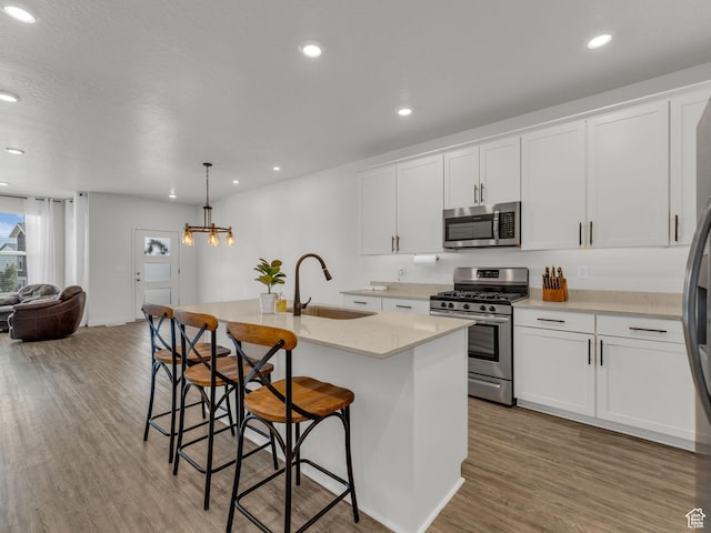 937 W Purpledisk Ct, Saratoga Springs, UT 84045 - kitchen with appliances with stainless steel finishes, wood finished floors, a center island with sink, open floor plan, and white cabinets