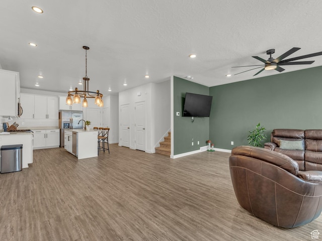 937 W Purpledisk Ct, Saratoga Springs, UT 84045 - living room featuring light wood-style flooring, a ceiling fan, stairs, recessed lighting, and a chandelier