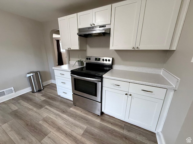 78 N N 3rd St N, Tooele, UT 84074 - kitchen featuring stainless steel electric range, under cabinet range hood, white cabinetry, arched walkways, and light countertops