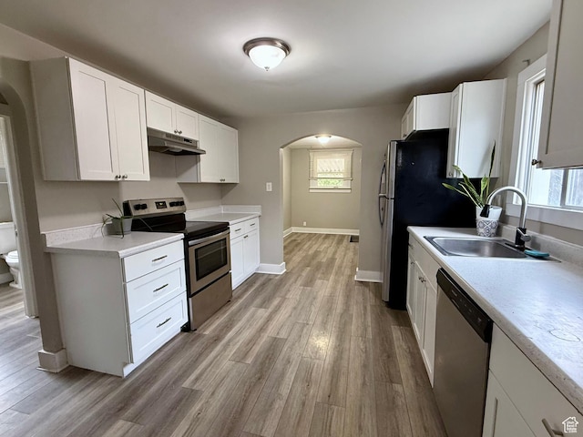 78 N N 3rd St N, Tooele, UT 84074 - kitchen featuring appliances with stainless steel finishes, arched walkways, under cabinet range hood, light wood-style floors, and light countertops