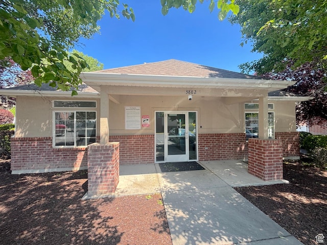 10521 S Sage Flats Way S, Jordan, UT 84009 - property entrance with brick siding, stucco siding, roof with shingles, and a patio area
