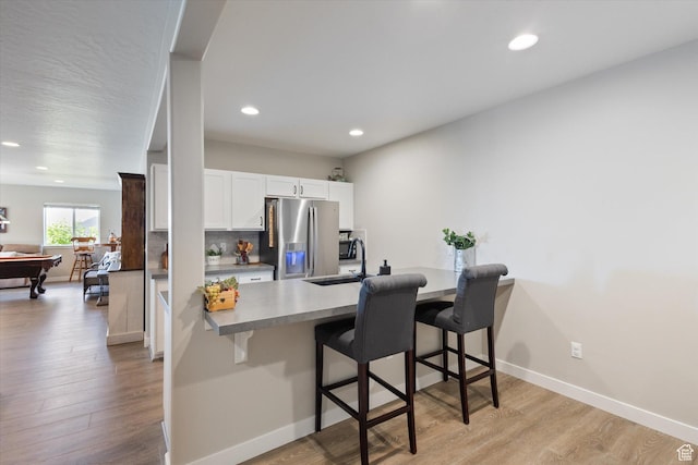 1414 S 790 E, Salem, UT 84653 - kitchen with stainless steel refrigerator with ice dispenser, a kitchen breakfast bar, light wood finished floors, white cabinetry, and recessed lighting