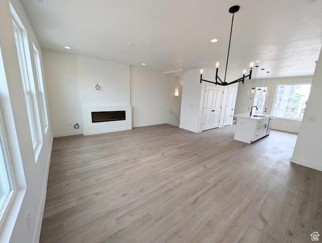 10634 S Cardinal Park Rd W Unit 148, South Jordan, UT 84009 - unfurnished living room featuring light wood-style floors, a fireplace, a chandelier, and recessed lighting