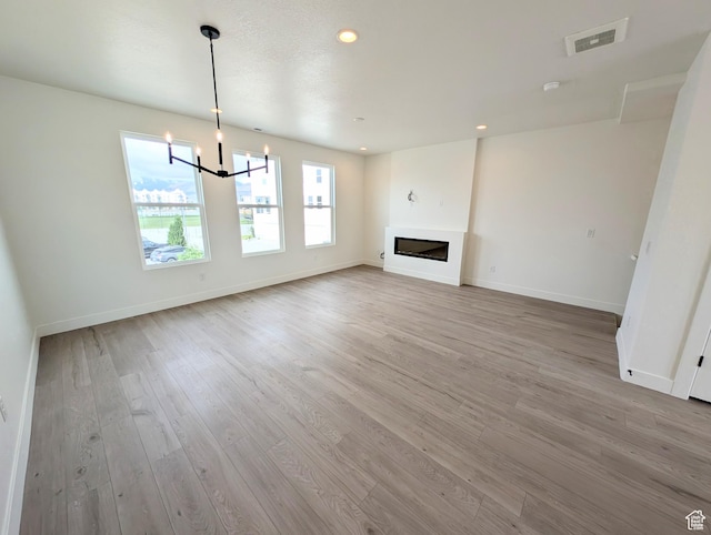 10634 S Cardinal Park Rd W Unit 148, South Jordan, UT 84009 - unfurnished living room with light wood-style flooring, a chandelier, recessed lighting, and a glass covered fireplace