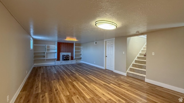 7166 S 4000 E, Price, UT 84501 - unfurnished living room with a textured ceiling, a brick fireplace, built in features, stairs, and wood finished floors