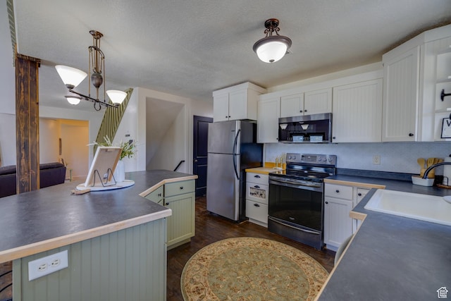 2599 S Foxridge Rd, Garden City, UT 84028 - kitchen featuring stainless steel appliances, dark countertops, a center island, white cabinetry, and a textured ceiling