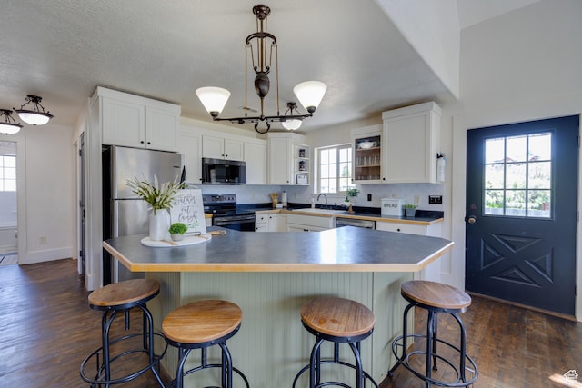 2599 S Foxridge Rd, Garden City, UT 84028 - kitchen featuring appliances with stainless steel finishes, white cabinetry, dark wood finished floors, a chandelier, and open shelves