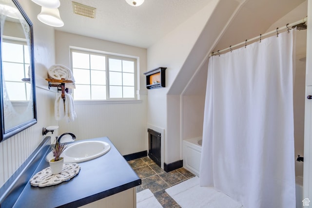 2599 S Foxridge Rd, Garden City, UT 84028 - bathroom with vanity, stone tile flooring, and shower / bath combination with curtain