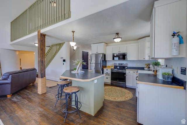 2599 S Foxridge Rd, Garden City, UT 84028 - kitchen with stainless steel appliances, open floor plan, dark wood finished floors, a breakfast bar, and a center island