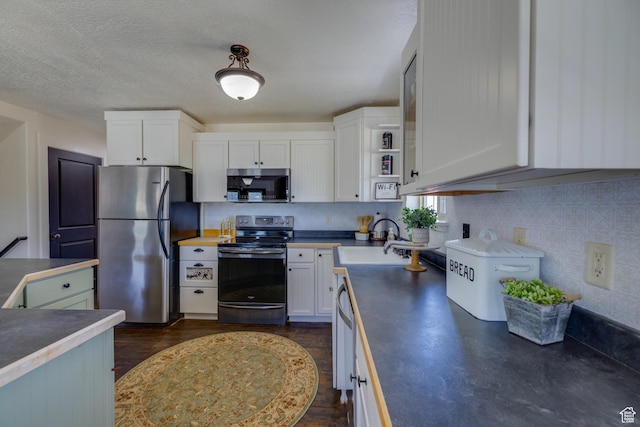 2599 S Foxridge Rd, Garden City, UT 84028 - kitchen featuring appliances with stainless steel finishes, dark countertops, white cabinets, and a textured ceiling