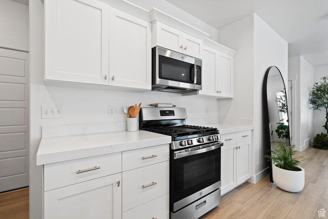 4892 E Lake Corner Dr, Eagle Mountain, UT 84005 - kitchen featuring stainless steel appliances, light wood-style floors, white cabinetry, and light stone countertops