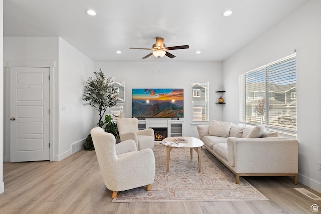4892 E Lake Corner Dr, Eagle Mountain, UT 84005 - living room with a ceiling fan, light wood-style flooring, recessed lighting, and a warm lit fireplace