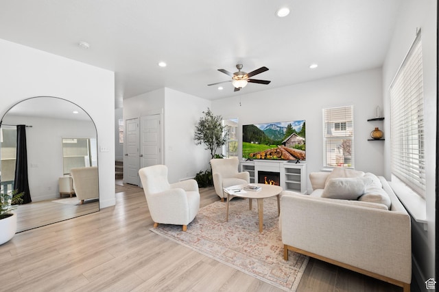 4892 E Lake Corner Dr, Eagle Mountain, UT 84005 - living room featuring recessed lighting, light wood-style floors, a warm lit fireplace, and ceiling fan