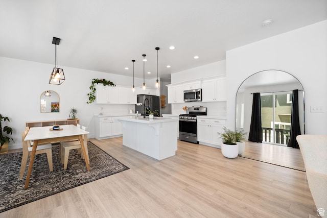 4892 E Lake Corner Dr, Eagle Mountain, UT 84005 - kitchen with stainless steel appliances, light countertops, an island with sink, a breakfast bar, and white cabinets
