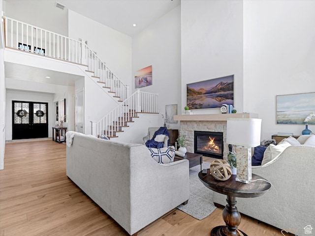 1172 E Candy Ln, American Fork, UT 84003 - living area with light wood-style flooring, a high ceiling, a stone fireplace, and stairs