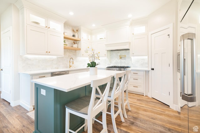 986 View Crest Ln, Kaysville, UT 84037 - kitchen with light wood-style floors, a kitchen island, white cabinetry, a breakfast bar area, and tasteful backsplash