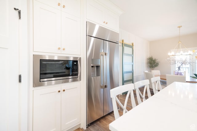 986 View Crest Ln, Kaysville, UT 84037 - kitchen with built in appliances, wood finished floors, a chandelier, white cabinets, and pendant lighting
