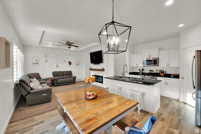 1752 S 570 W, Provo, UT 84601 - dining room with ceiling fan, recessed lighting, light wood-style flooring, a tray ceiling, and a large fireplace