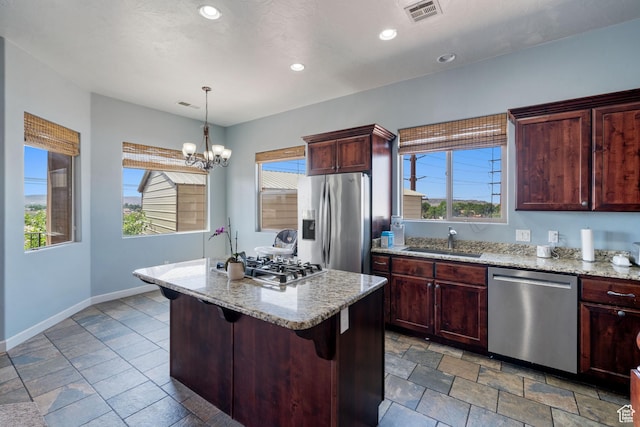 2752 E 50 S, St George, UT 84790 - kitchen with appliances with stainless steel finishes, a chandelier, a kitchen island, light stone countertops, and decorative light fixtures