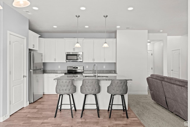 5423 W Black Hills Ln, Herriman, UT 84096 - kitchen with stainless steel appliances, a kitchen breakfast bar, white cabinetry, light stone counters, and recessed lighting