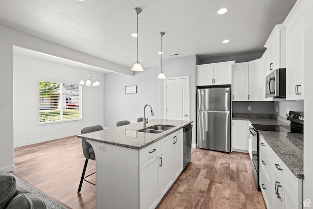 5423 W Black Hills Ln, Herriman, UT 84096 - kitchen featuring appliances with stainless steel finishes, a kitchen breakfast bar, light wood-style flooring, a chandelier, and white cabinets