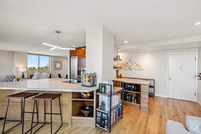 777 E S Temple Unit 13B, Salt Lake City, UT 84102 - kitchen with a kitchen bar, light wood-type flooring, light countertops, recessed lighting, and stainless steel oven