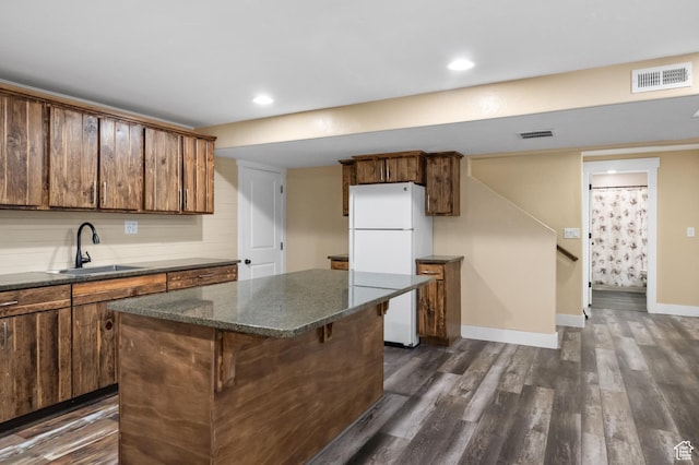 5194 Hedgerose Dr, Herriman, UT 84096 - kitchen with freestanding refrigerator, dark wood finished floors, a kitchen breakfast bar, a center island, and dark stone counters