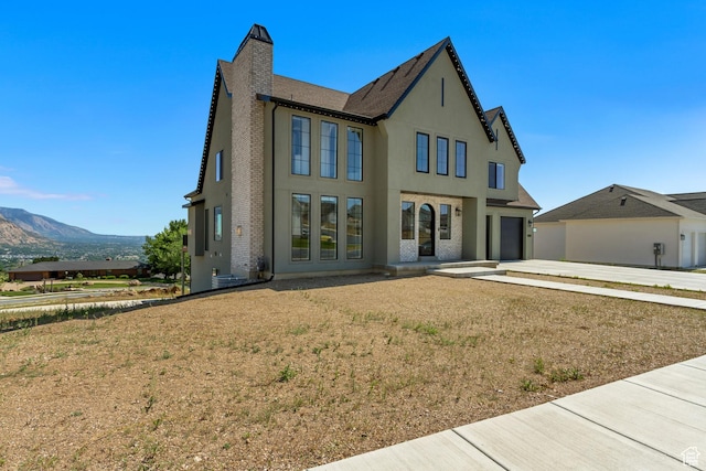 481 E 3675 N, North Ogden, UT 84414 - view of front of house featuring driveway, stucco siding, a garage, a chimney, and a mountain view