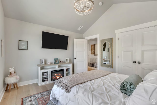 481 E 3675 N, North Ogden, UT 84414 - bedroom with a chandelier, a closet, light wood finished floors, a glass covered fireplace, and high vaulted ceiling