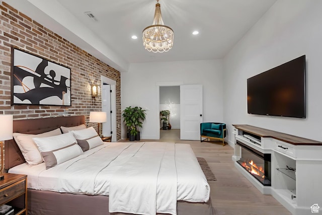481 E 3675 N, North Ogden, UT 84414 - bedroom with brick wall, light wood finished floors, a chandelier, a glass covered fireplace, and recessed lighting