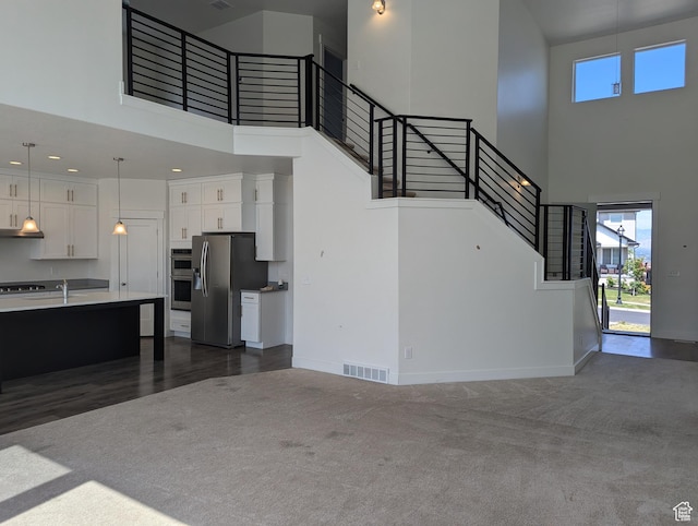 57 N Midland Dr, Saratoga Springs, UT 84045 - unfurnished living room featuring a high ceiling, stairway, and dark carpet