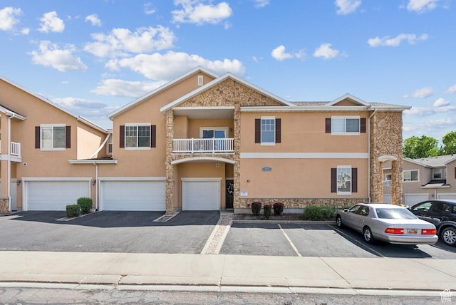 1676 E 1080 S, Provo, UT 84604 - townhome / multi-family property with stone siding, stucco siding, an attached garage, a balcony, and driveway
