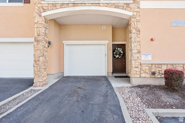 1676 E 1080 S, Provo, UT 84604 - property entrance featuring stone siding, a garage, stucco siding, and asphalt driveway