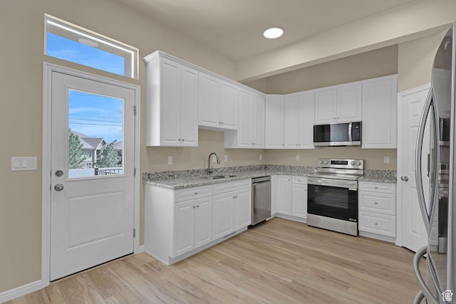 454 E 850 S Unit 106, Brigham City, UT 84302 - kitchen with appliances with stainless steel finishes, white cabinetry, light wood-style floors, and light stone counters
