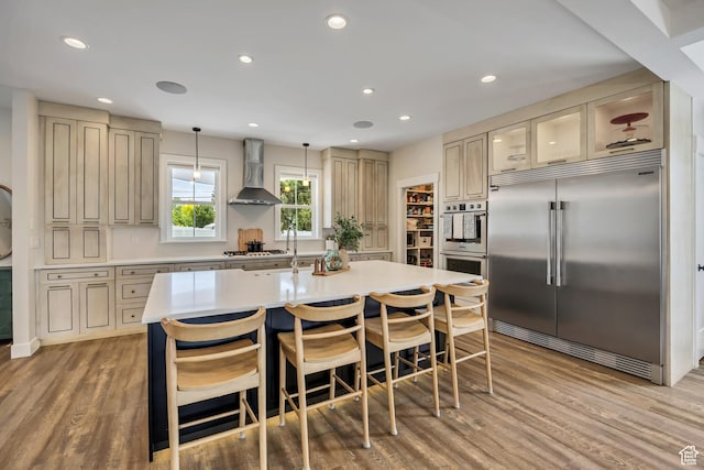 2040 E Lambourne Ave, Millcreek, UT 84109 - kitchen with stainless steel appliances, wall chimney range hood, cream cabinets, light countertops, and recessed lighting