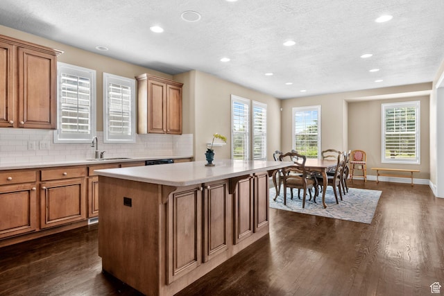 4892 W Veeroma Way S, Jordan, UT 84009 - kitchen featuring a textured ceiling, dark wood finished floors, recessed lighting, a kitchen island, and brown cabinets