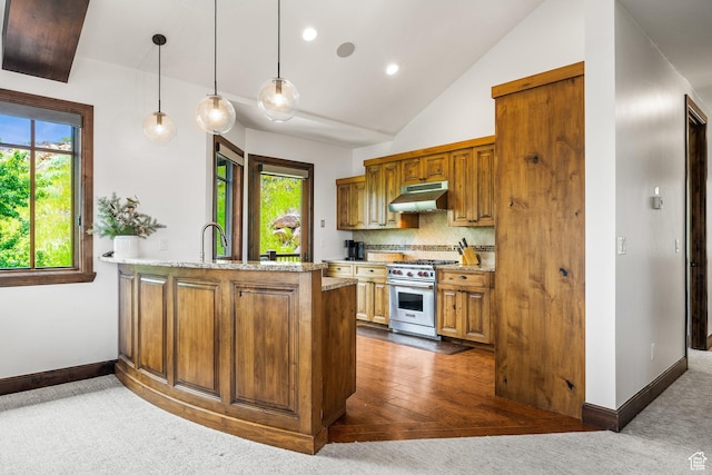 4121 Fairway Ln Unit A1, Park City, UT 84098 - kitchen with high end range, under cabinet range hood, brown cabinets, a peninsula, and lofted ceiling