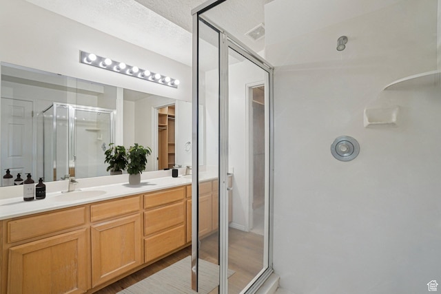 4964 Boulder Glen Cir, West Jordan, UT 84088 - bathroom featuring a stall shower, double vanity, a spacious closet, wood finished floors, and a textured ceiling