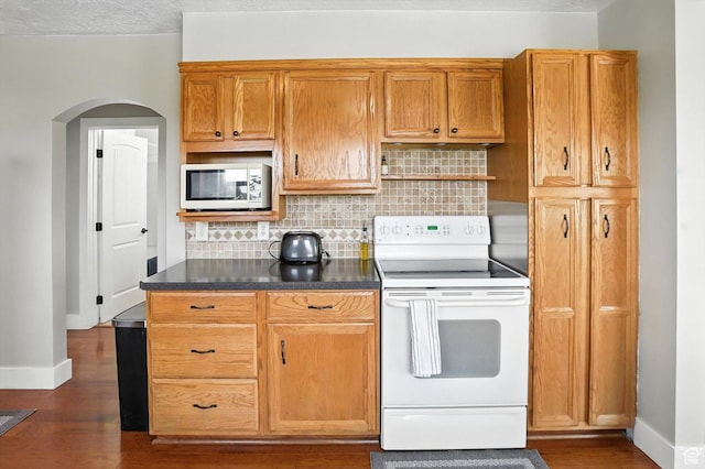 11395 N 4400 W, Tremonton, UT 84337 - kitchen with white appliances, arched walkways, dark wood-style flooring, tasteful backsplash, and dark countertops