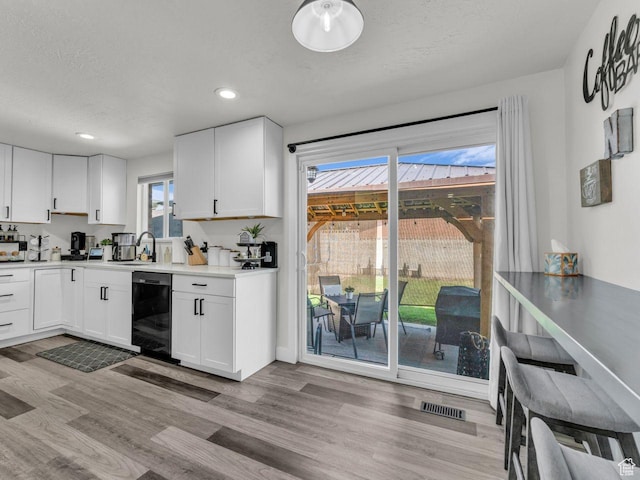 4332 W Losee Dr, West Valley City, UT 84120 - kitchen featuring black dishwasher, light wood finished floors, white cabinetry, recessed lighting, and light countertops