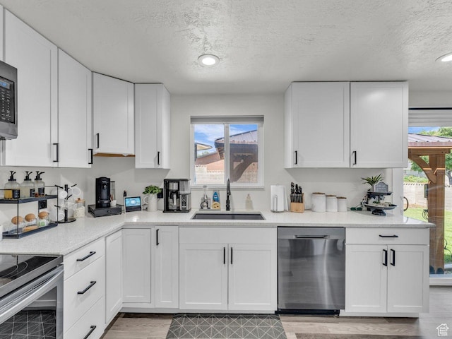 4332 W Losee Dr, West Valley City, UT 84120 - kitchen featuring dishwasher, a textured ceiling, white cabinets, light wood finished floors, and recessed lighting