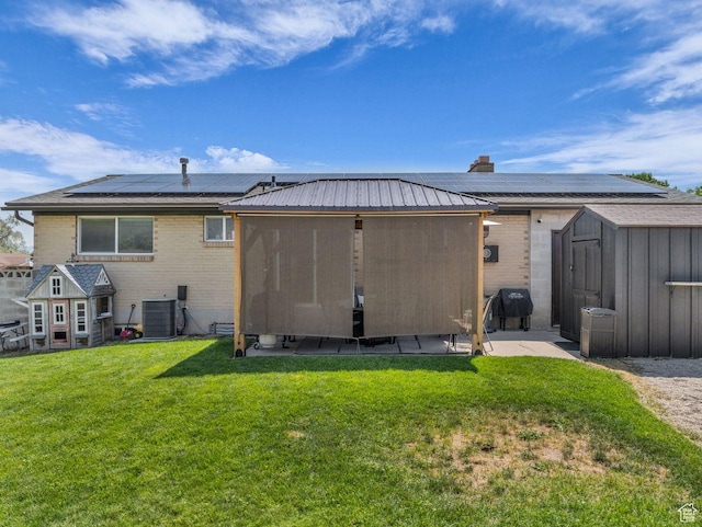 4332 W Losee Dr, West Valley City, UT 84120 - back of house with a shed, roof mounted solar panels, brick siding, and a yard