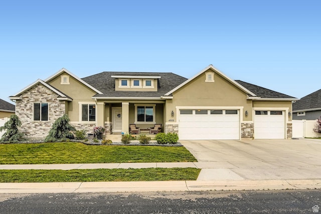 4909 N Cliffrose Dr, Eagle Mountain, UT 84005 - view of front of home with stone siding, stucco siding, covered porch, an attached garage, and concrete driveway