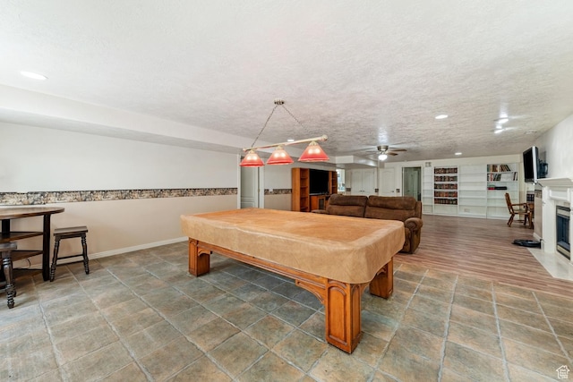 29 N Meadowlark Cir, Grantsville, UT 84029 - playroom with billiards, a ceiling fan, a fireplace with flush hearth, built in shelves, and a textured ceiling