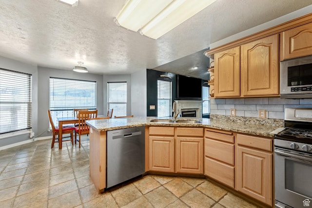 29 N Meadowlark Cir, Grantsville, UT 84029 - kitchen with appliances with stainless steel finishes, a peninsula, light stone counters, a textured ceiling, and light brown cabinets