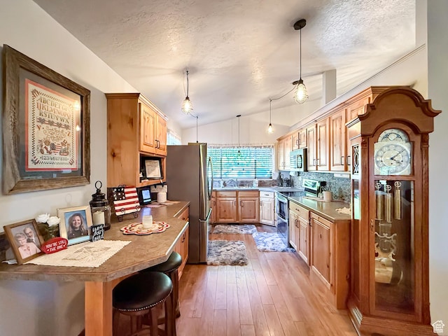 280 W 2400 S, Perry, UT 84302 - kitchen with appliances with stainless steel finishes, a textured ceiling, vaulted ceiling, light wood-style floors, and decorative light fixtures