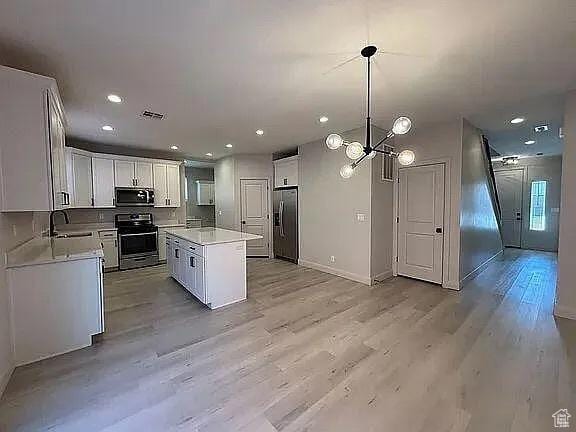 840 N Twin Lakes Dr Unit 414, St George, UT 84790 - kitchen featuring appliances with stainless steel finishes, light countertops, light wood-type flooring, a chandelier, and white cabinets